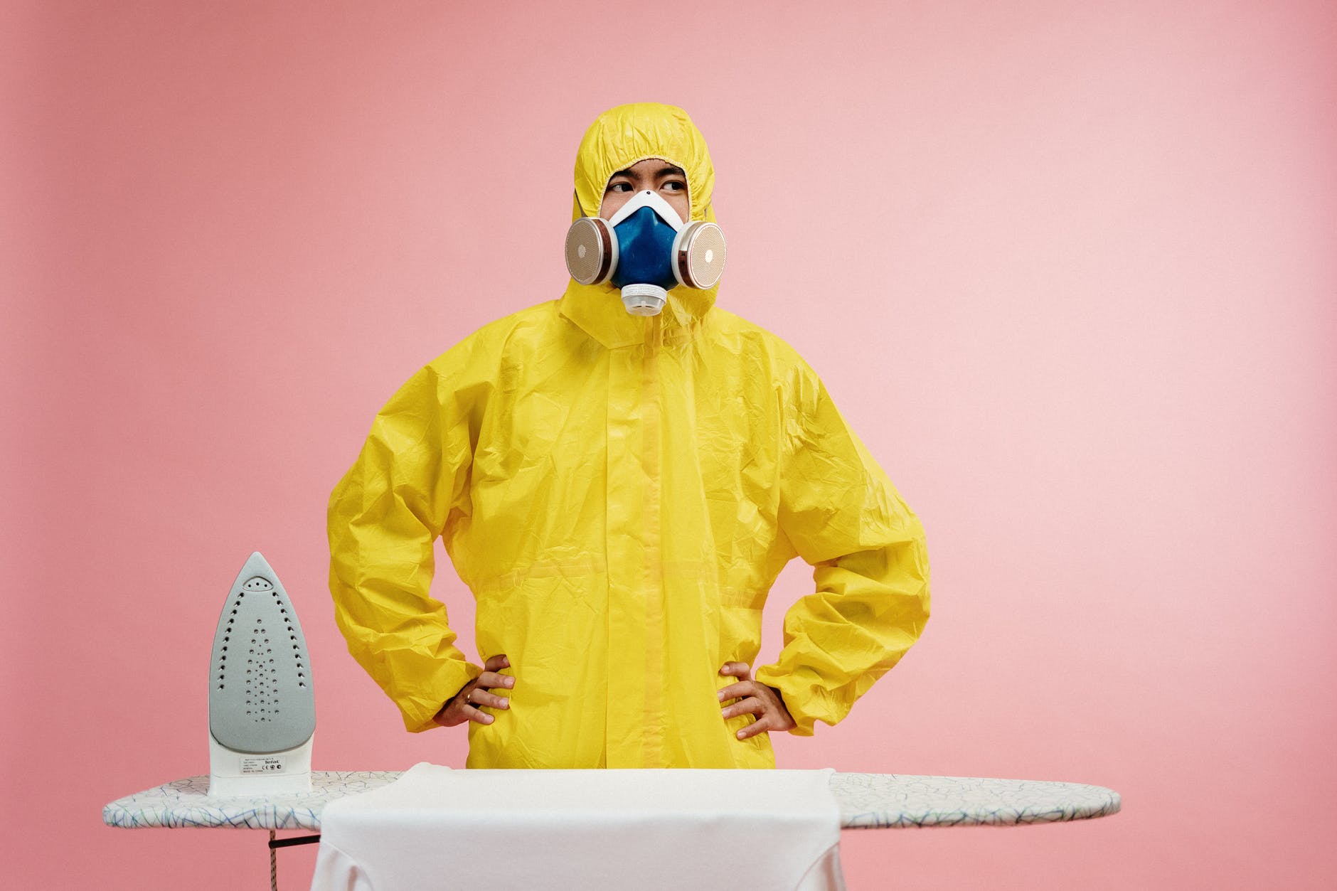 man in coveralls standing by ironing board